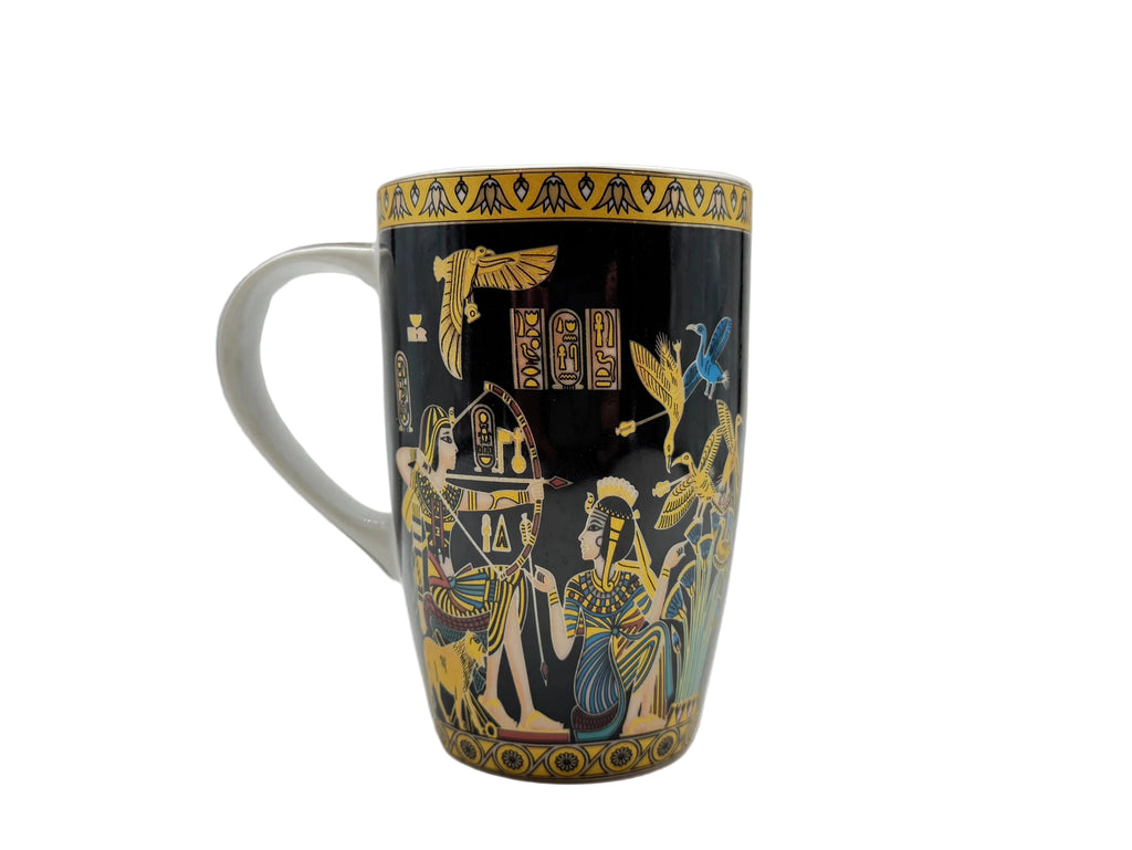 Handle-side angle of the Mesu Hunter Mug displaying colorful Egyptian figures, gold detailing, and papyrus artwork in a studio setup