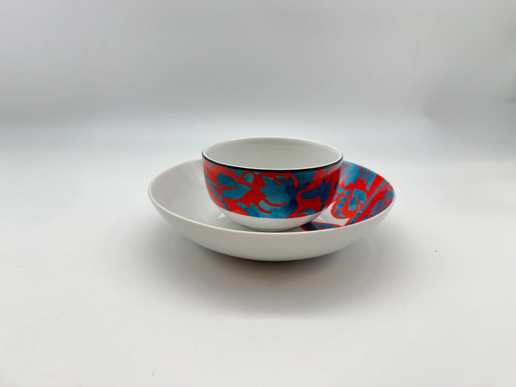Porcelain bowl placed on matching deep plate in red and blue pattern