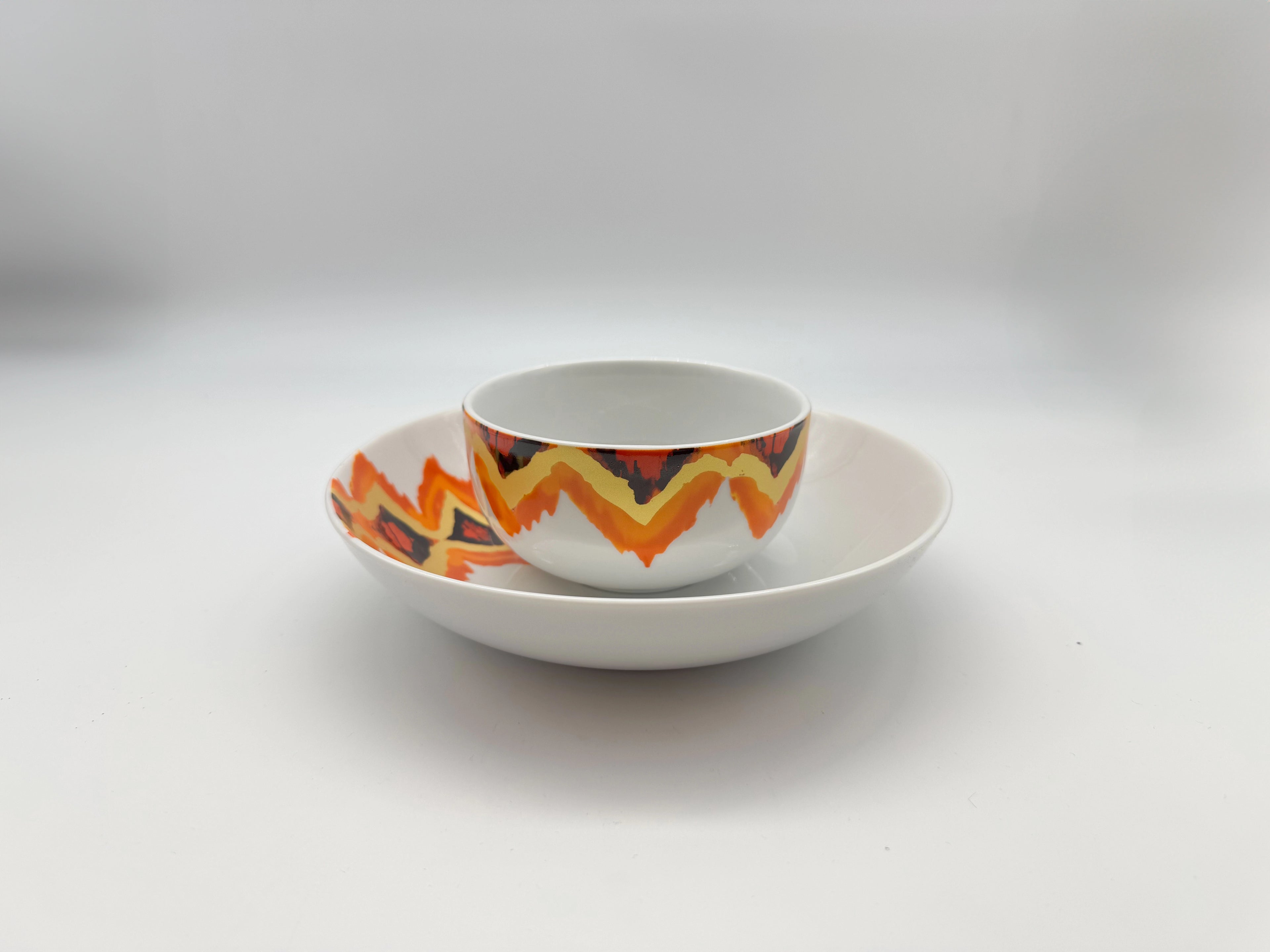 Sunset Zigzag porcelain bowl and plate stacking set with orange and red patterns